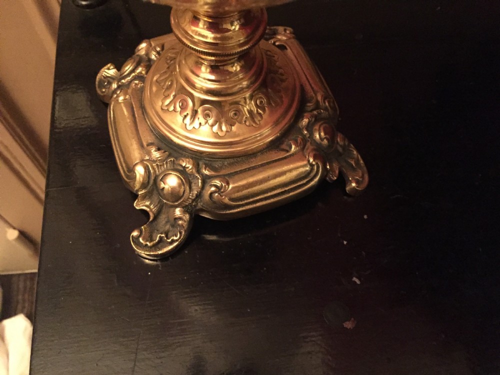An Art Nouveau table lamp featuring an ornate cast brass base, a clear patterned glass reservoir, and a frosted spherical glass shade. View X