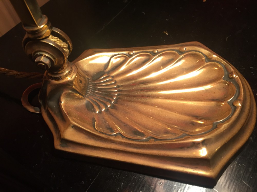 An Edwardian adjustable brass desk lamp featuring a shell-shaped base, a curved arm, and an illuminated fluted cranberry pink glass shade. View VIII