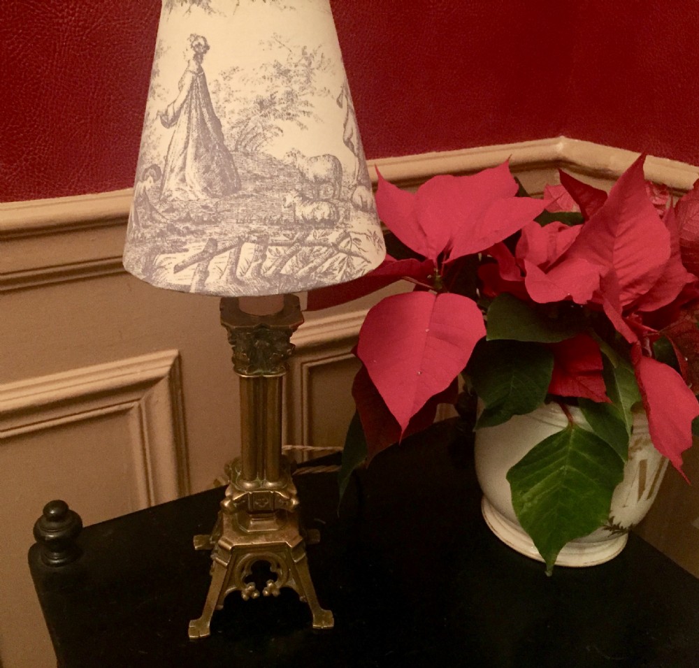 An antique French bronze column table lamp featuring a fluted shaft and Corinthian capital topped with a Toile de Jouy patterned shade. View IX