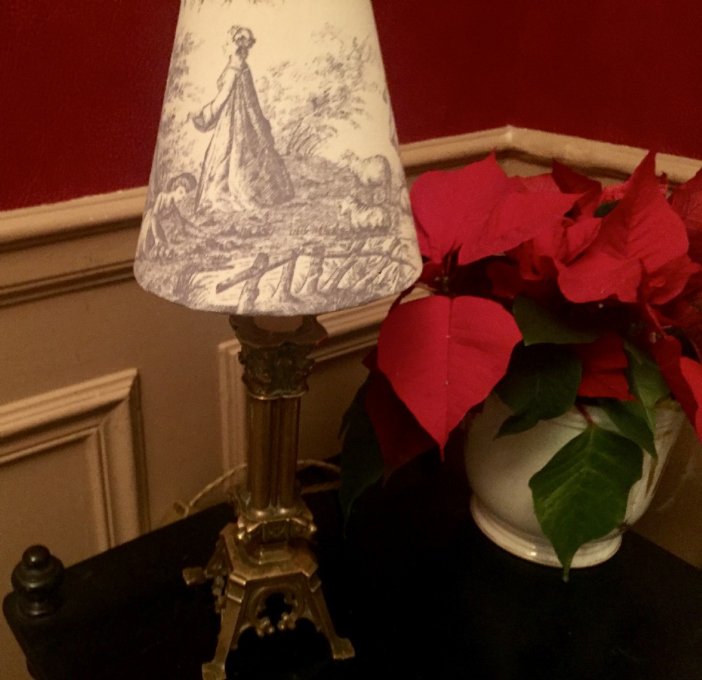 An antique French bronze column table lamp featuring a fluted shaft and Corinthian capital topped with a Toile de Jouy patterned shade. View VII