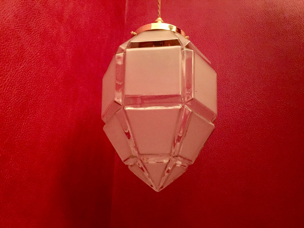 An Art Deco geometric faceted frosted glass pendant light featuring a brass gallery top and pointed lower tip. View VI