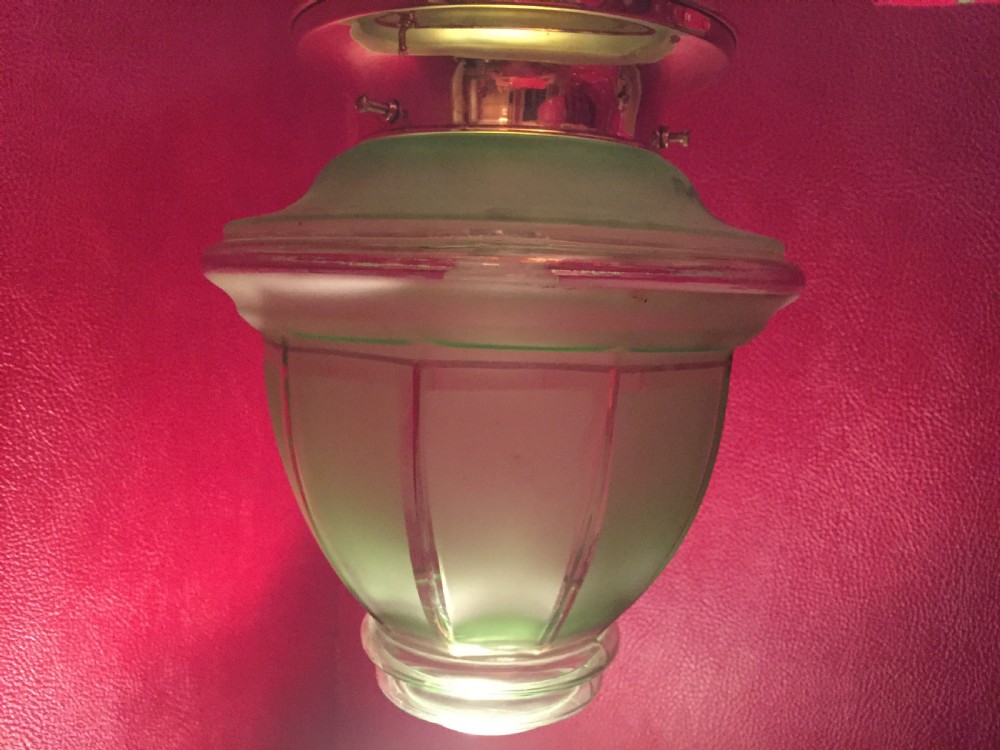 An illuminated Art Deco ceiling globe made of green frosted glass with ribbed panel details. View IV
