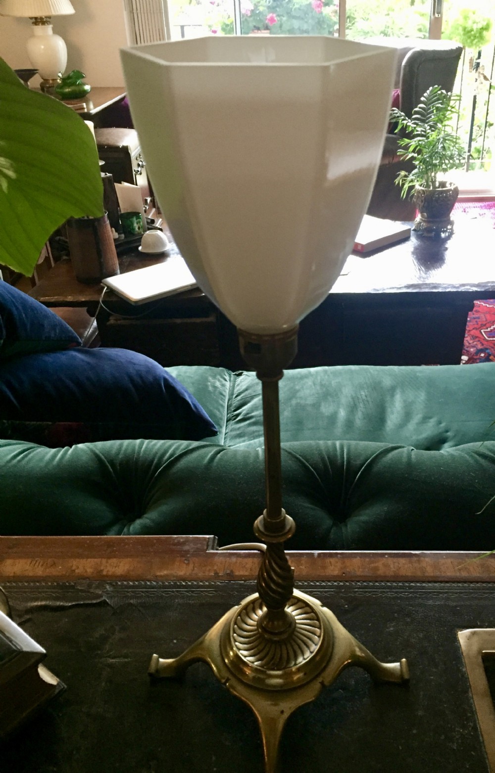 An Edwardian brass table lamp featuring a tripod base, a twisted column stem, and a faceted white opaline glass shade.