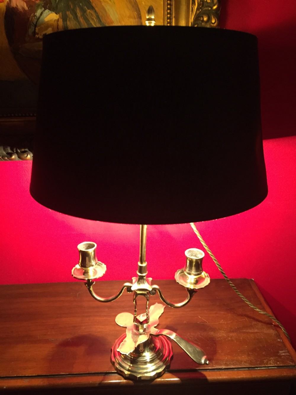 An antique French brass desk lamp with twin candlestick arms and a dark rounded lampshade.