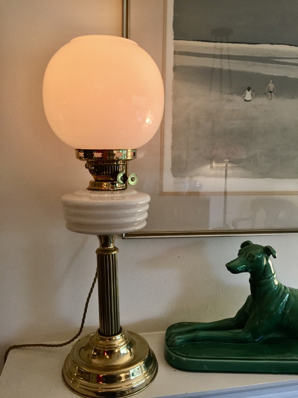 An Edwardian brass table lamp converted from an oil burner, featuring a fluted column, ribbed opaline collar, and spherical glass shade.