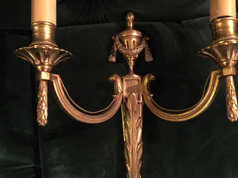 A pair of nineteenth-century French Napoleon III gilt bronze two-arm wall sconces featuring classical urn finials, drapery swags, and acanthus leaf detailing. View V