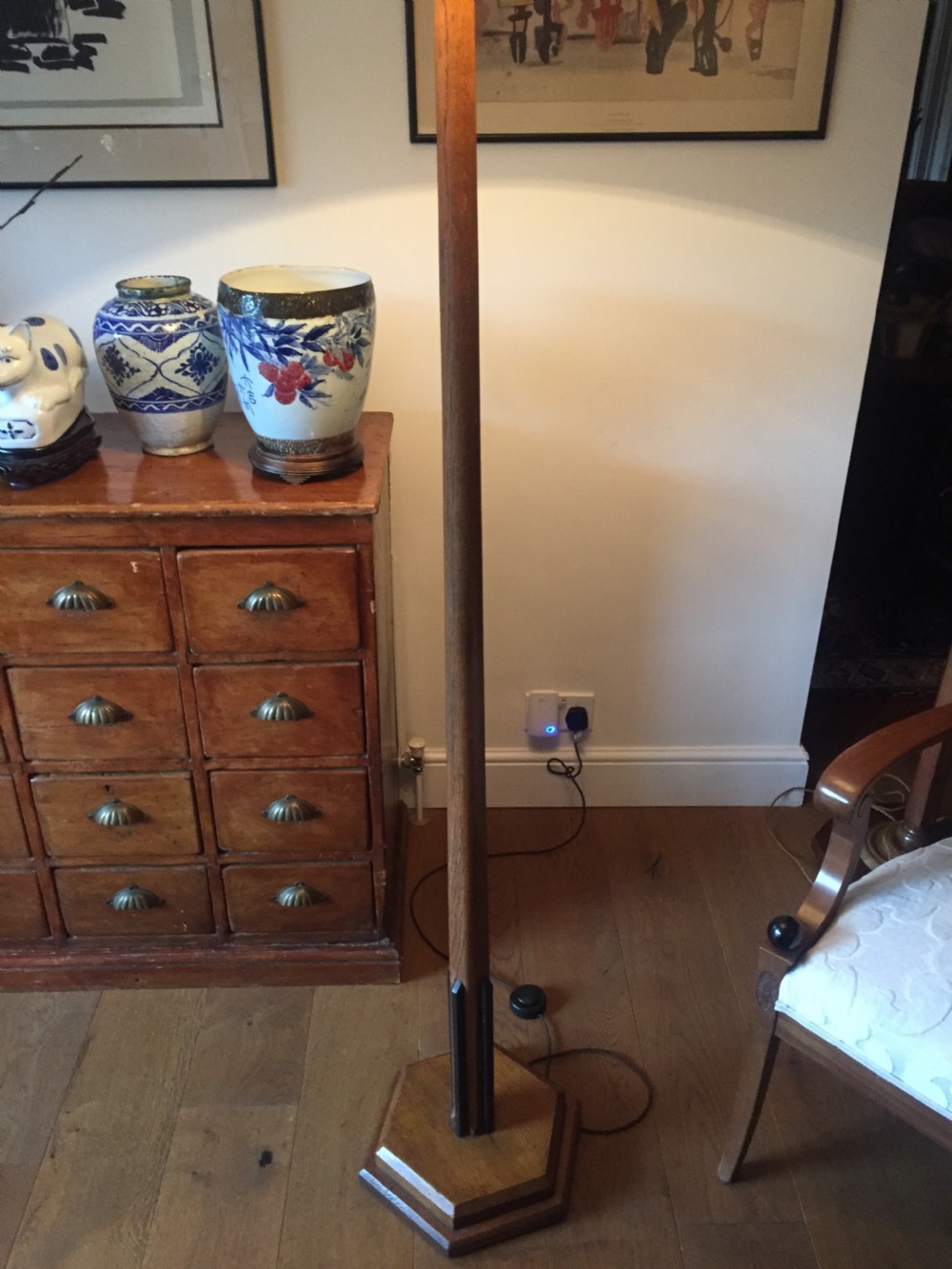 An Art Deco standard lamp with a tapered golden oak column, dark ebony detailing near the bottom, and a stepped octagonal wooden base.