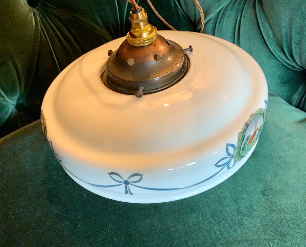 A white glass ceiling pendant shade with a brass top gallery, decorated with hand-painted blue ribbons and a central medallion depicting a cottage. View VI