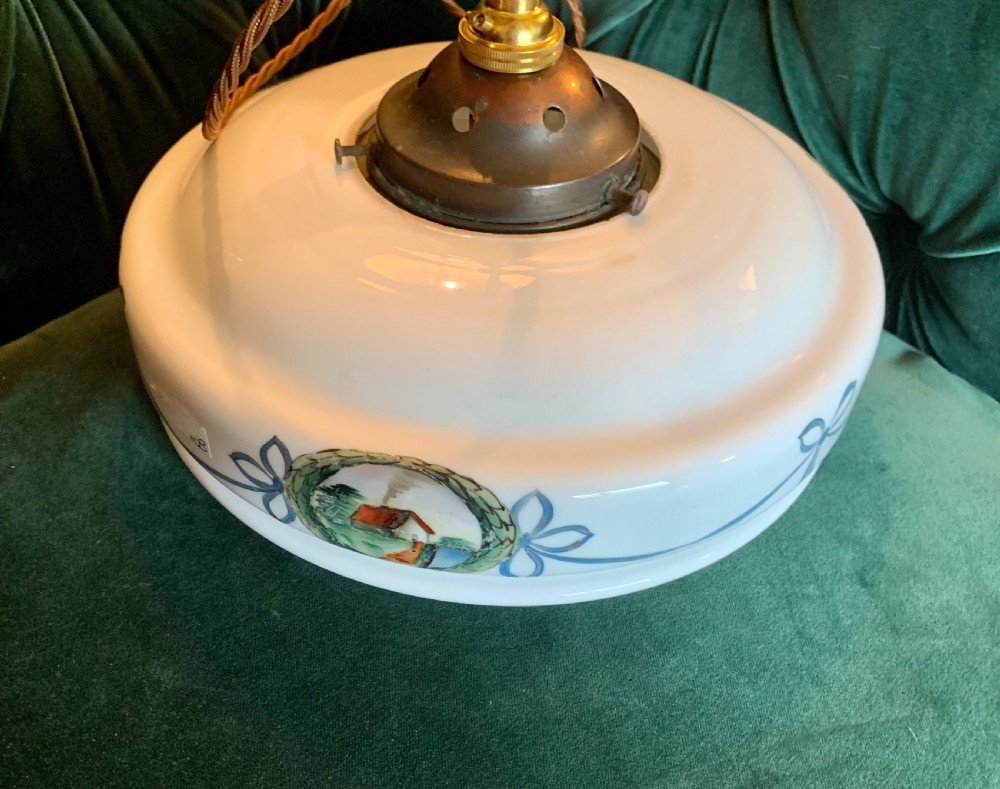 A white glass ceiling pendant shade with a brass top gallery, decorated with hand-painted blue ribbons and a central medallion depicting a cottage. View VII