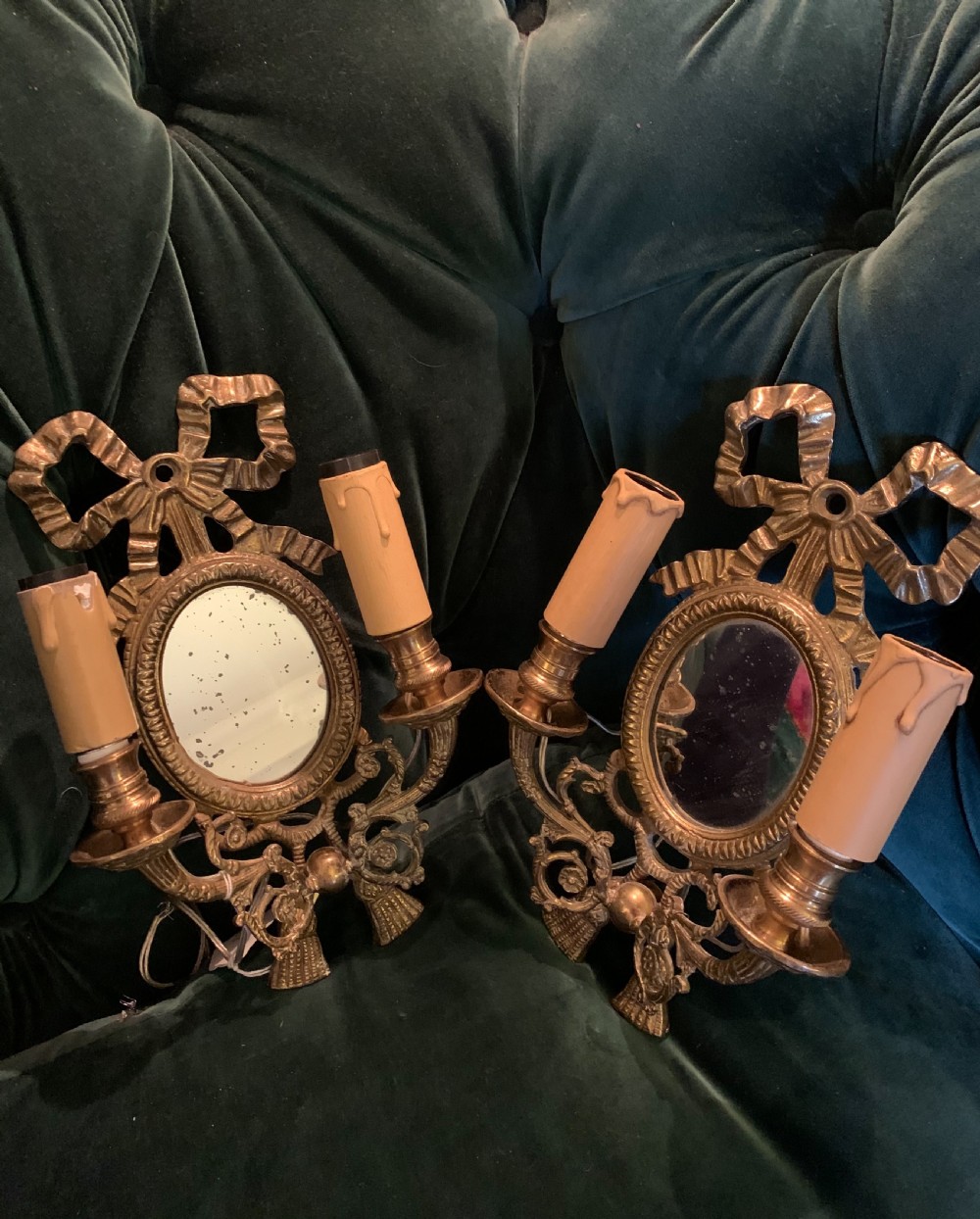A pair of antique French gilt bronze wall sconces featuring ribbon bow cresting, oval mirror backplates, and two candle arms. View II