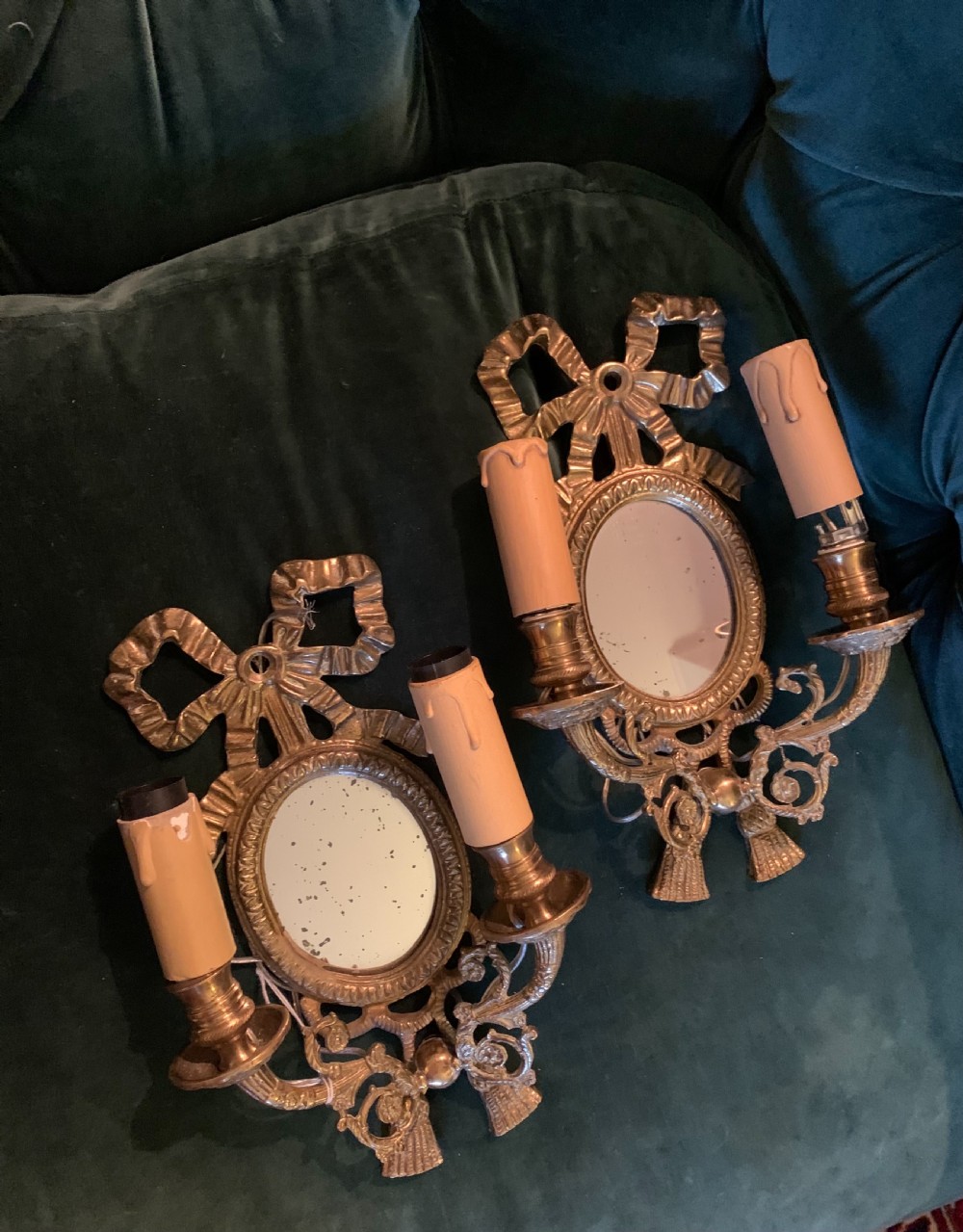 A pair of antique French gilt bronze wall sconces featuring ribbon bow cresting, oval mirror backplates, and two candle arms. View V