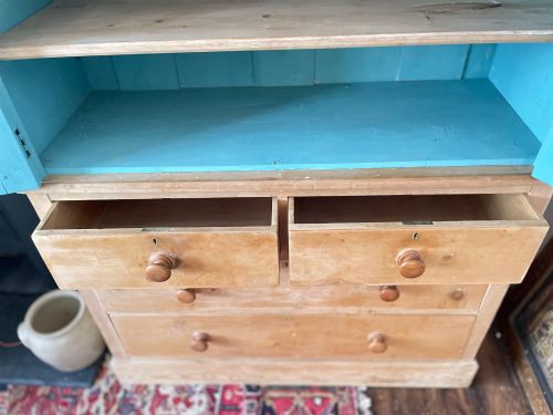 fig 4. A Victorian waxed pine glazed bookcase featuring two upper glass cabinet doors with a blue painted interior over a chest of four drawers with turned knobs.