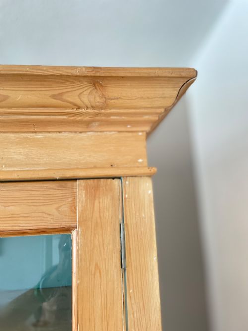 fig 5. A Victorian waxed pine glazed bookcase featuring two upper glass cabinet doors with a blue painted interior over a chest of four drawers with turned knobs.