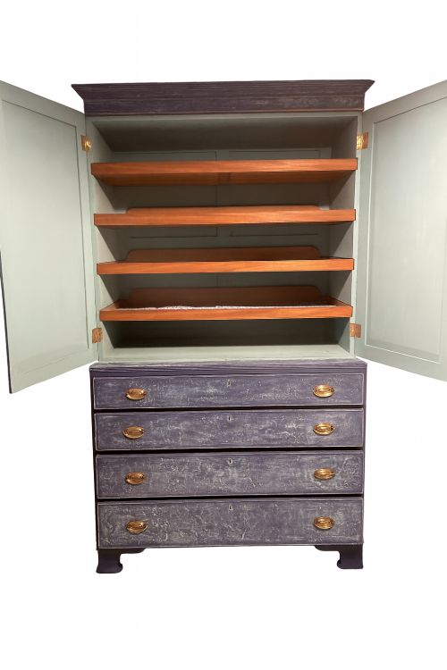 fig 1. A tall 19th-century Regency linen press featuring a distressed blue painted finish, two upper cupboard doors, and four lower drawers with brass handles.