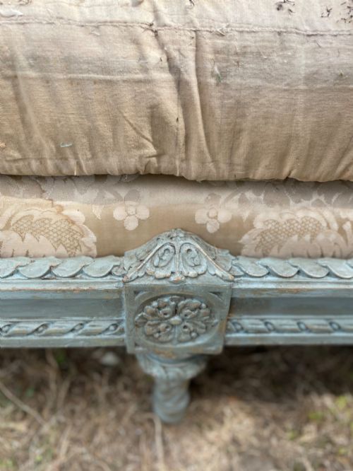 fig 5. A French Louis XVI style daybed featuring a grey-painted curved timber frame with woven cane panels, fitted with a cream linen mattress cushion and two bolster pillows.