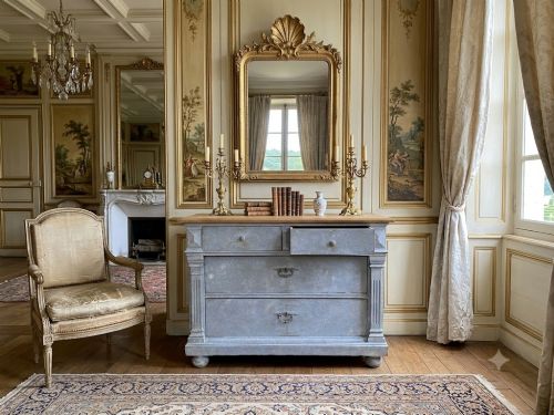 fig 1. A French Gustavian style chest of drawers featuring a natural wood top, pale blue distressed paint finish, fluted corner pilasters, carved diamond-point details, and metal drop handles.