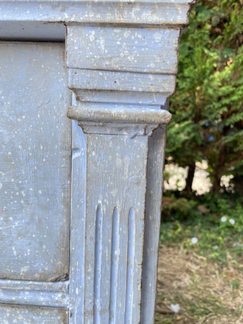 fig 3. A French Gustavian style chest of drawers featuring a natural wood top, pale blue distressed paint finish, fluted corner pilasters, carved diamond-point details, and metal drop handles.