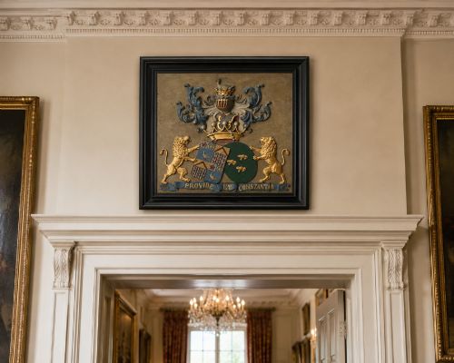 fig 1. A framed 19th-century Dutch heraldic marriage plaque depicting two carved gilt lion supporters holding alliance coats of arms under a helmet crest and motto banner.