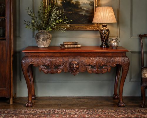 fig 5. An Edwardian George II style mahogany serving table with an intricately carved apron featuring a central mask motif, raised on cabriole legs with claw and ball feet.