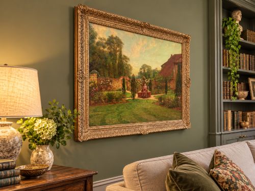 fig 3. An antique oil painting depicting a woman seated in a walled garden surrounded by trees and a country house, set in an ornate gilded frame.