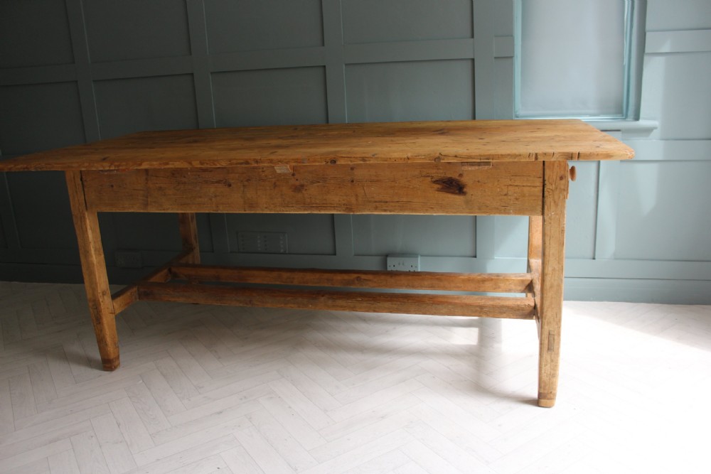 A 19th century rectangular Irish pine farmhouse table featuring square legs, lower H-stretchers, and a warm timber finish. View X