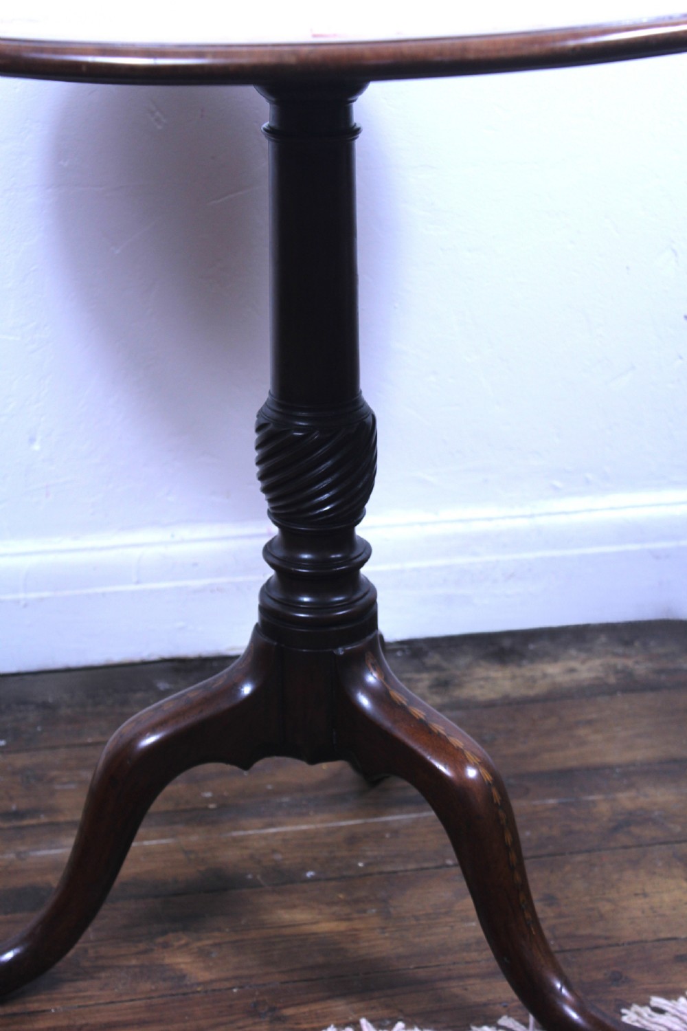 An 18th-century George III mahogany tilt-top tripod table with a circular crossbanded top tilted vertically on a turned stem and splayed legs. View II