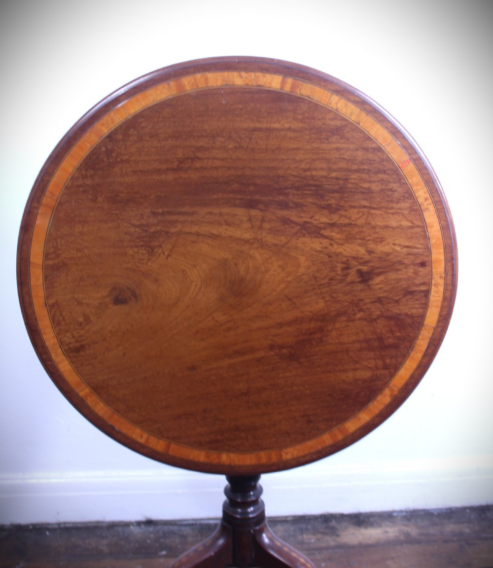 An 18th-century George III mahogany tilt-top tripod table with a circular crossbanded top tilted vertically on a turned stem and splayed legs. View III