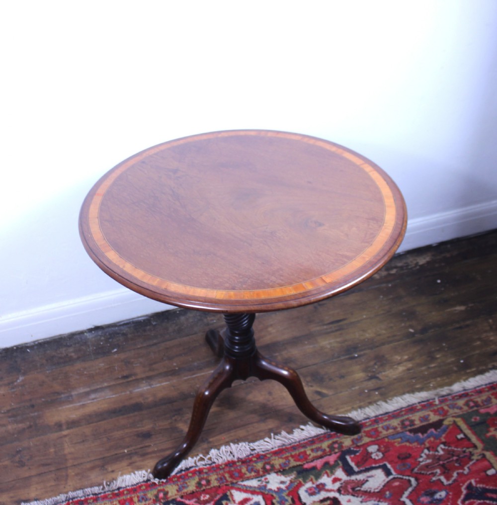 An 18th-century George III mahogany tilt-top tripod table with a circular crossbanded top tilted vertically on a turned stem and splayed legs. View VII