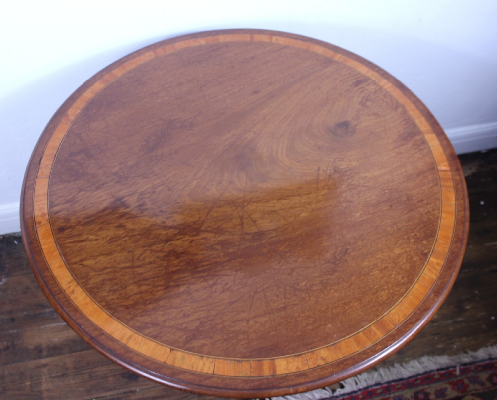 An 18th-century George III mahogany tilt-top tripod table with a circular crossbanded top tilted vertically on a turned stem and splayed legs. View IX