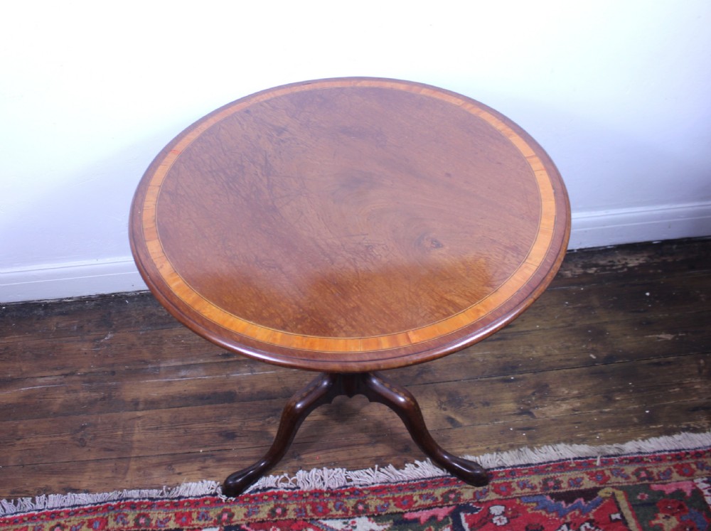 An 18th-century George III mahogany tilt-top tripod table with a circular crossbanded top tilted vertically on a turned stem and splayed legs. View XI