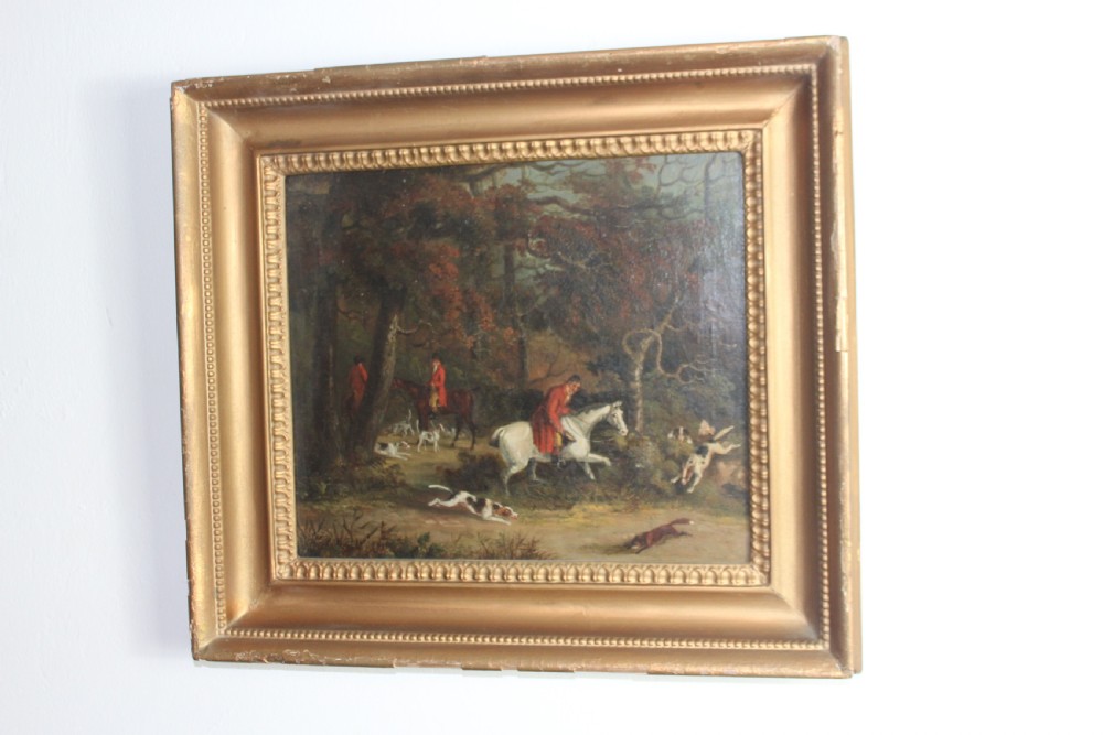 An early 19th-century oil painting depicting horse riders in red coats with hunting hounds pursuing a fox through a woodland, set in a gilded frame. View III