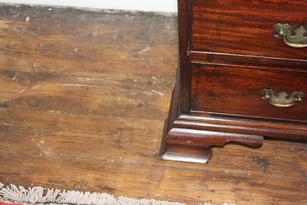 A George II mahogany chest of drawers featuring four graduated drawers with brass handles and supported on ogee bracket feet. View X