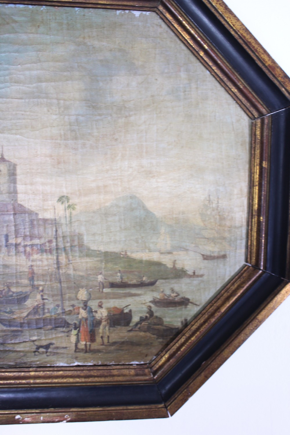 An octagonal framed early 19th-century oil painting depicting a Brazilian coastal landscape with colonial buildings, figures along the shore, and boats on the water. View X