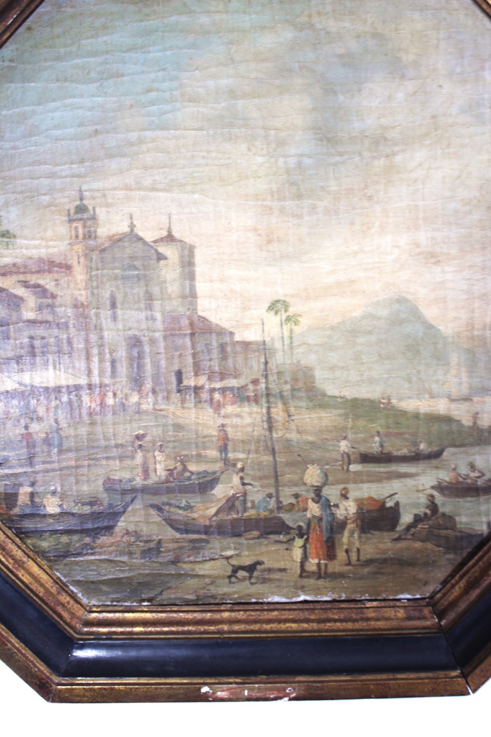 An octagonal framed early 19th-century oil painting depicting a Brazilian coastal landscape with colonial buildings, figures along the shore, and boats on the water. View XIV