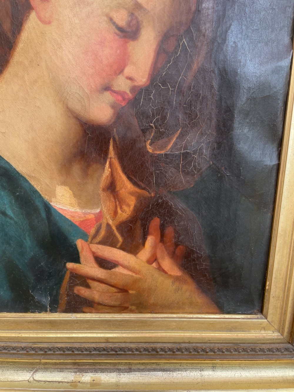 An 18th-century oil painting depicting the Virgin Mary with downcast eyes and folded hands, set within a moulded gilt wood frame. View X