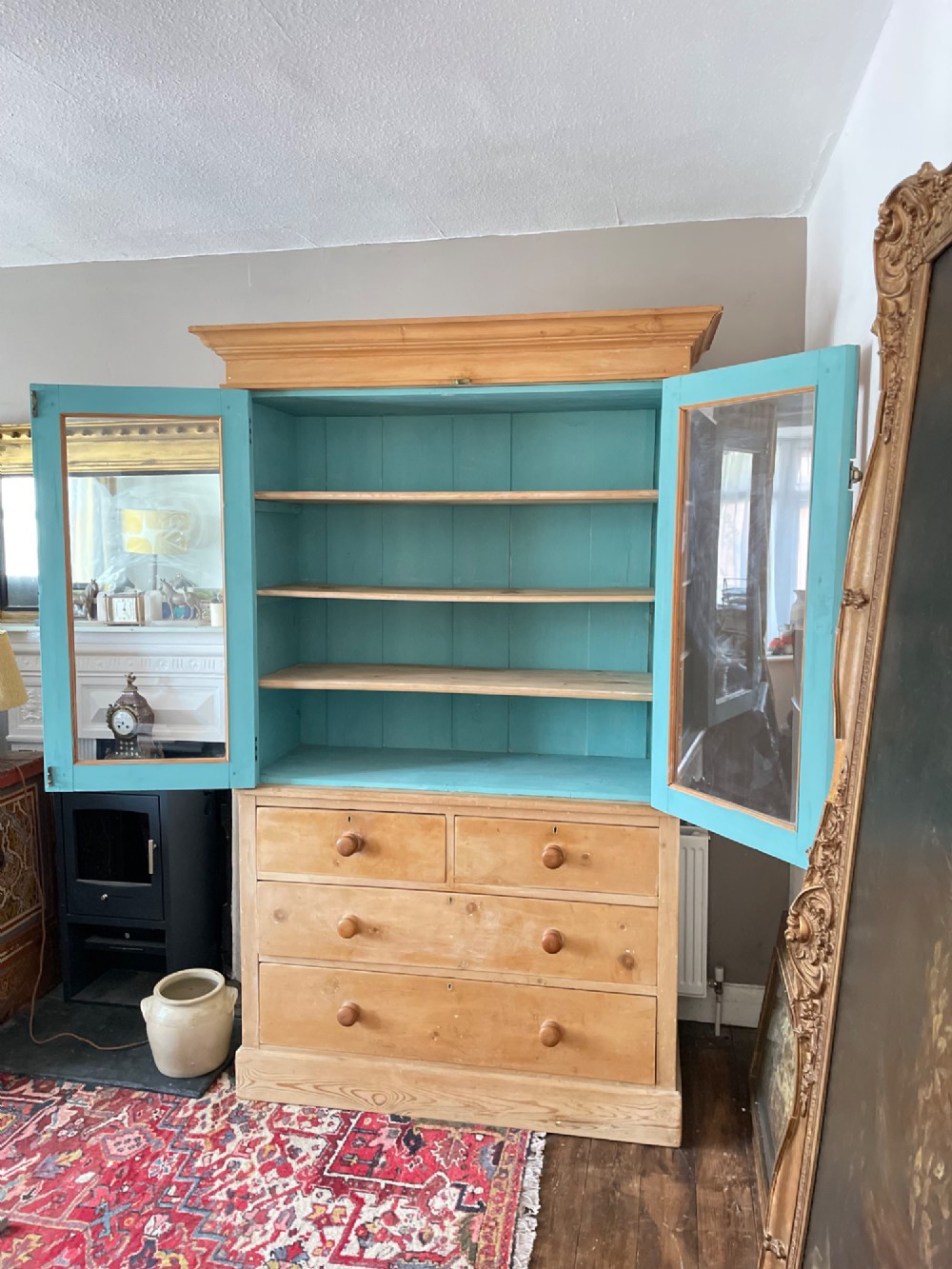 A Victorian waxed pine glazed bookcase featuring two upper glass cabinet doors with a blue painted interior over a chest of four drawers with turned knobs. View VII