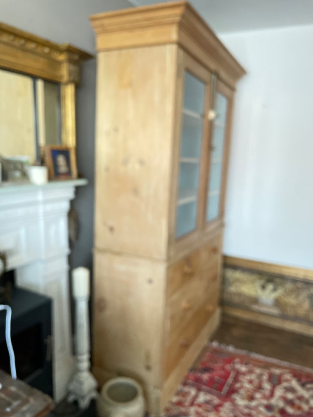 A Victorian waxed pine glazed bookcase featuring two upper glass cabinet doors with a blue painted interior over a chest of four drawers with turned knobs. View X