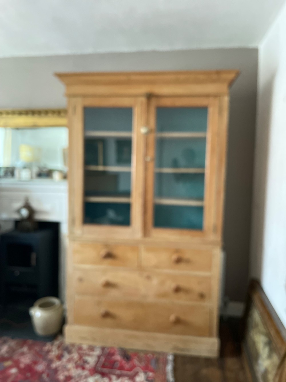 A Victorian waxed pine glazed bookcase featuring two upper glass cabinet doors with a blue painted interior over a chest of four drawers with turned knobs. View XI
