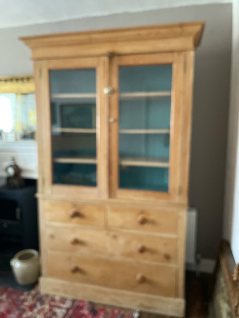A Victorian waxed pine glazed bookcase featuring two upper glass cabinet doors with a blue painted interior over a chest of four drawers with turned knobs. View XIII