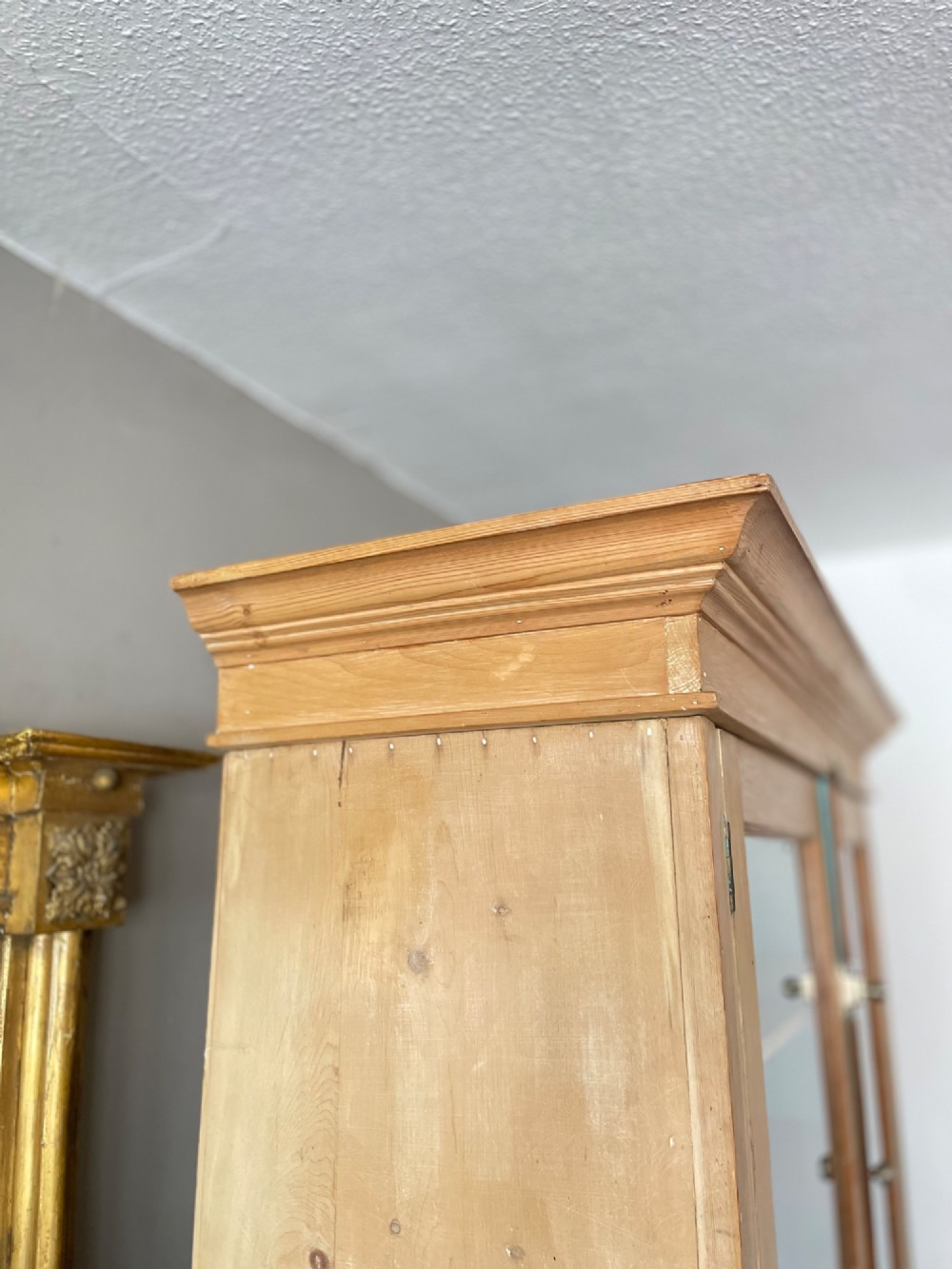 A Victorian waxed pine glazed bookcase featuring two upper glass cabinet doors with a blue painted interior over a chest of four drawers with turned knobs. View XIV