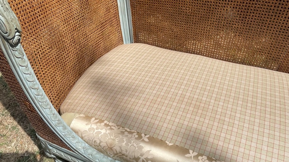 A French Louis XVI style daybed featuring a grey-painted curved timber frame with woven cane panels, fitted with a cream linen mattress cushion and two bolster pillows. View XI