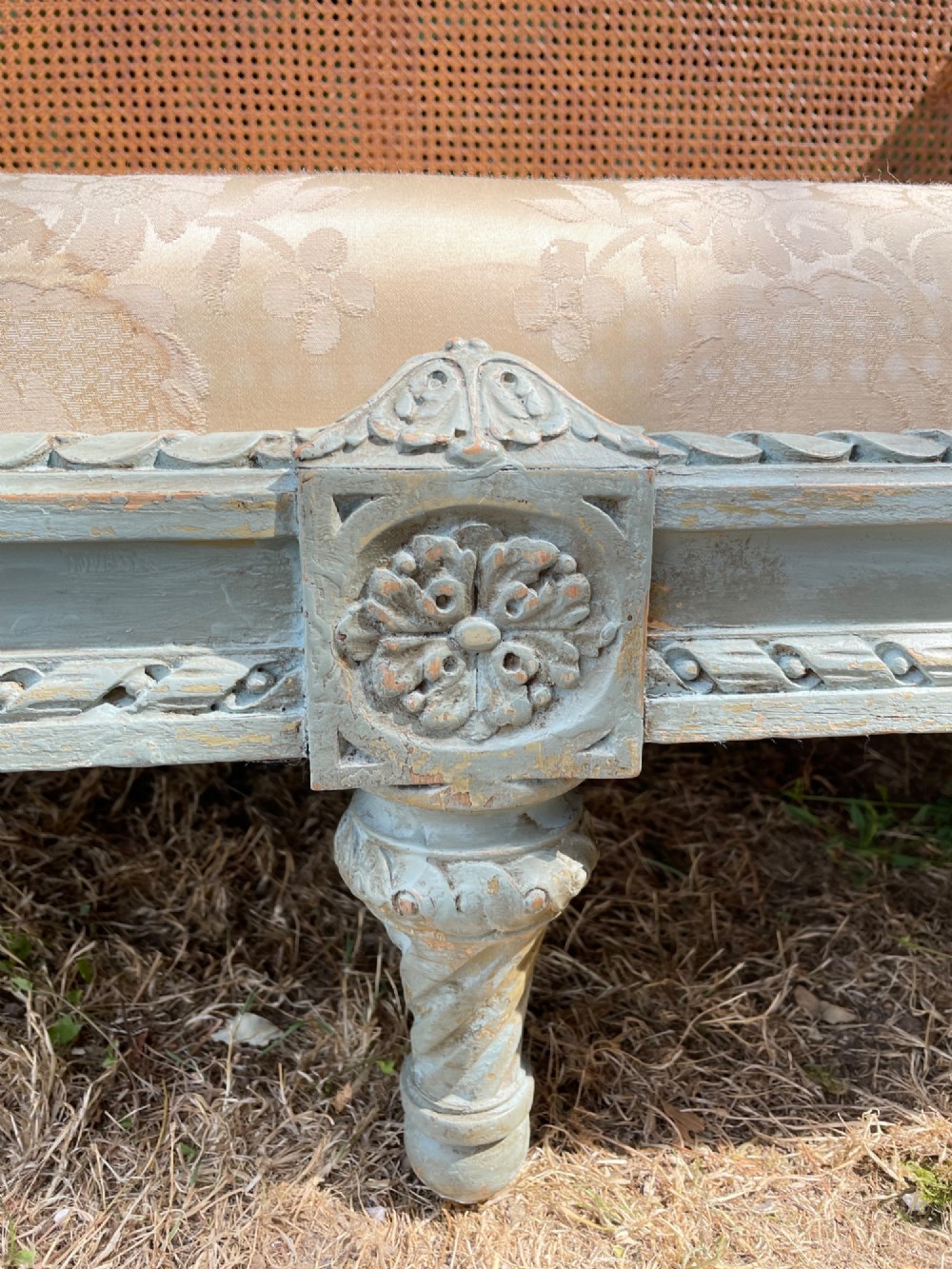 A French Louis XVI style daybed featuring a grey-painted curved timber frame with woven cane panels, fitted with a cream linen mattress cushion and two bolster pillows. View XV