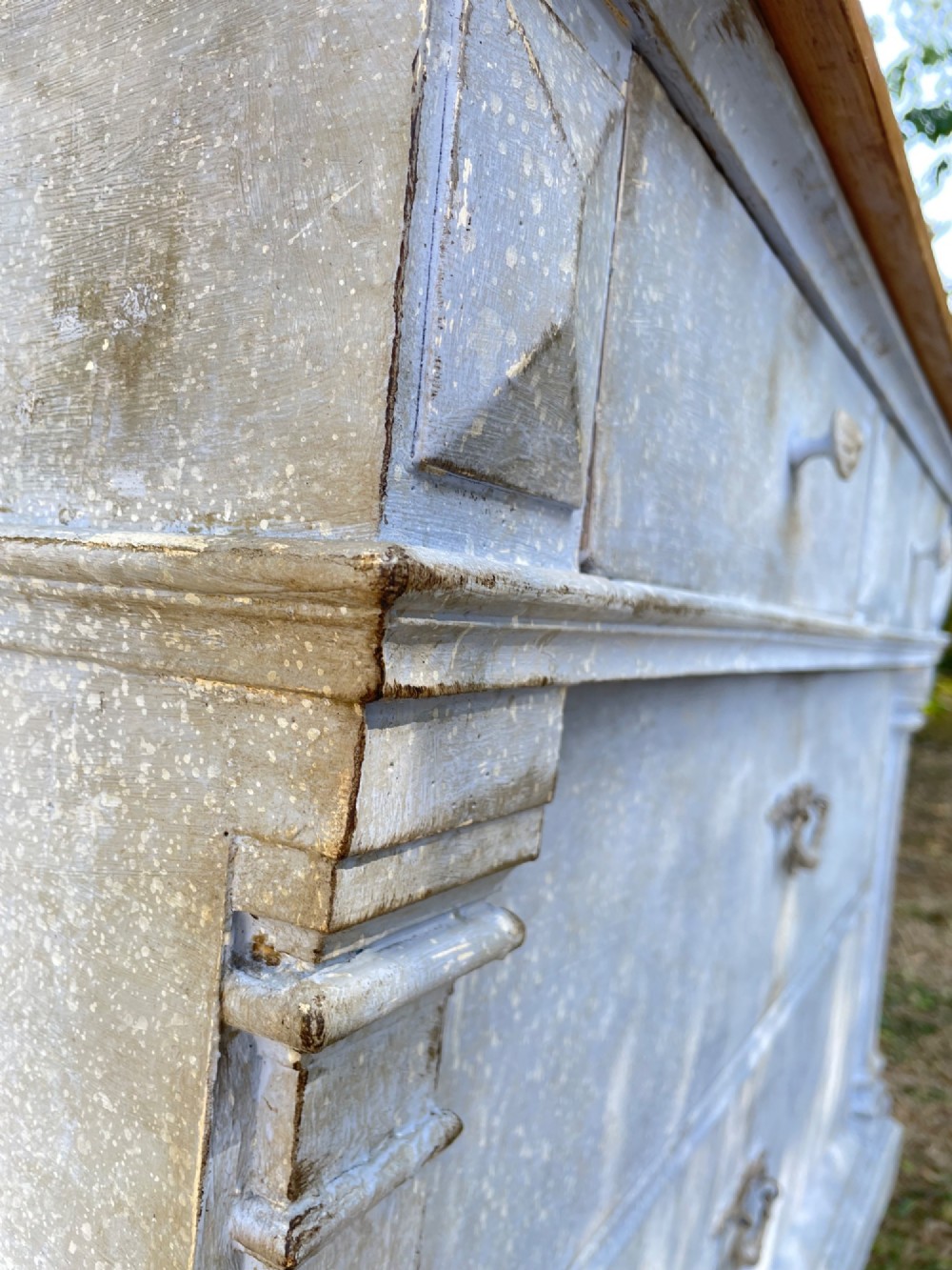A French Gustavian style chest of drawers featuring a natural wood top, pale blue distressed paint finish, fluted corner pilasters, carved diamond-point details, and metal drop handles. View VII