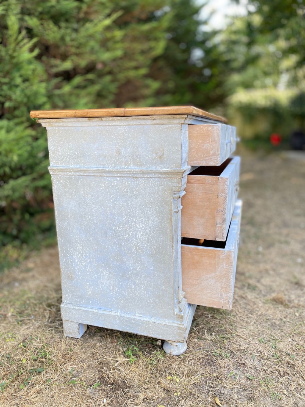 A French Gustavian style chest of drawers featuring a natural wood top, pale blue distressed paint finish, fluted corner pilasters, carved diamond-point details, and metal drop handles. View XIII