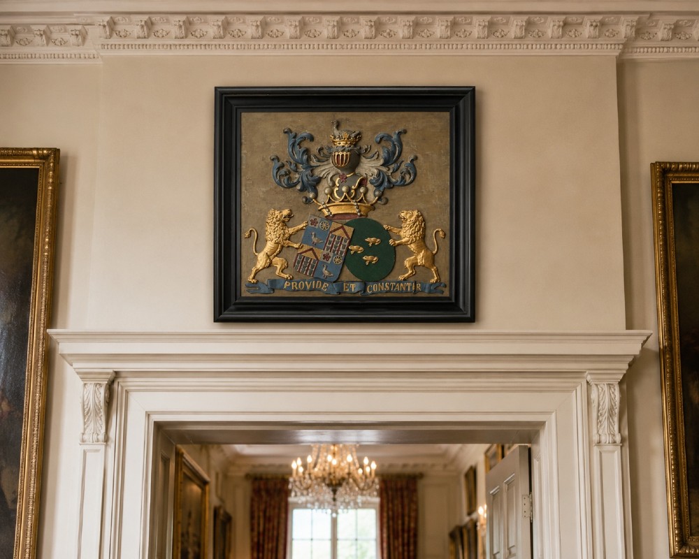 A framed 19th-century Dutch heraldic marriage plaque depicting two carved gilt lion supporters holding alliance coats of arms under a helmet crest and motto banner. View II
