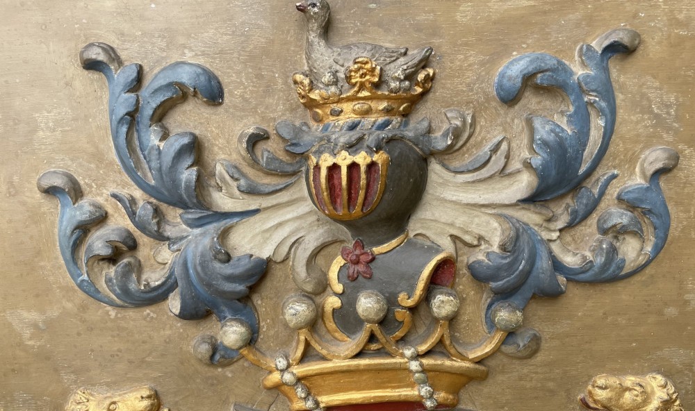 A framed 19th-century Dutch heraldic marriage plaque depicting two carved gilt lion supporters holding alliance coats of arms under a helmet crest and motto banner. View V