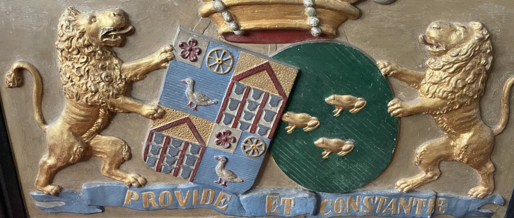 A framed 19th-century Dutch heraldic marriage plaque depicting two carved gilt lion supporters holding alliance coats of arms under a helmet crest and motto banner. View X