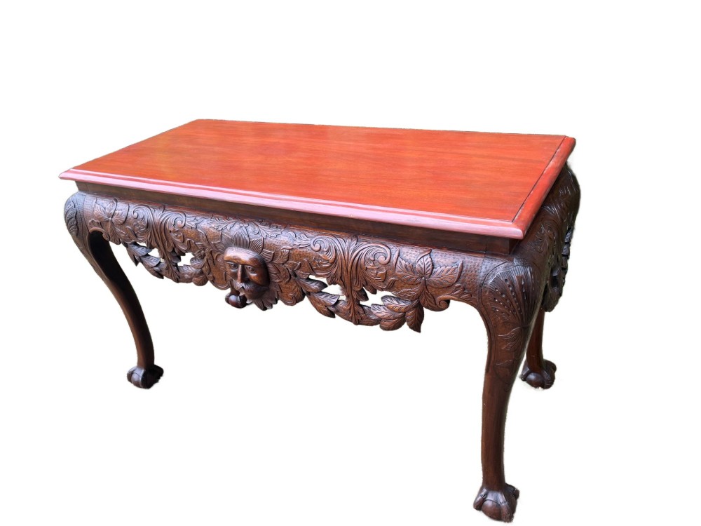 An Edwardian George II style mahogany serving table with an intricately carved apron featuring a central mask motif, raised on cabriole legs with claw and ball feet. View V