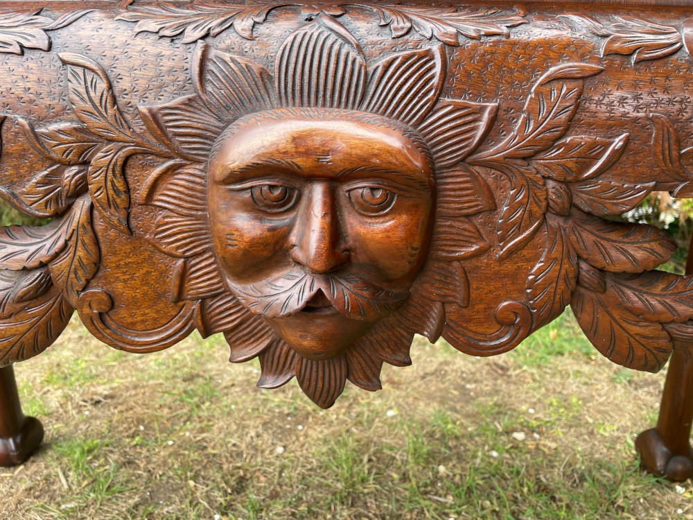 An Edwardian George II style mahogany serving table with an intricately carved apron featuring a central mask motif, raised on cabriole legs with claw and ball feet. View VI