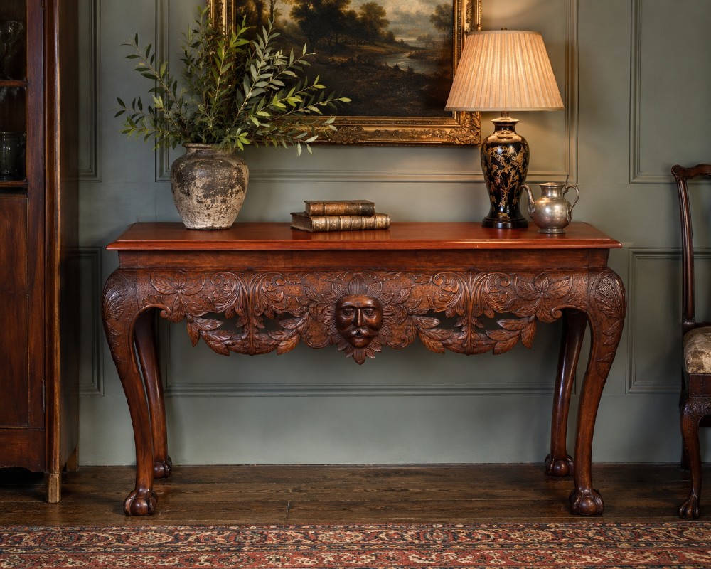 An Edwardian George II style mahogany serving table with an intricately carved apron featuring a central mask motif, raised on cabriole legs with claw and ball feet. View VII